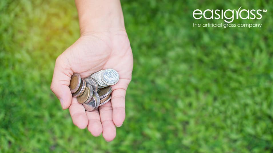 Hand holding money on green artificial grass